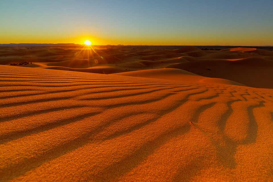 Rippled orange sand dunes of the Erg Chebbi in the Sahara Desert, Morocco, at sunset