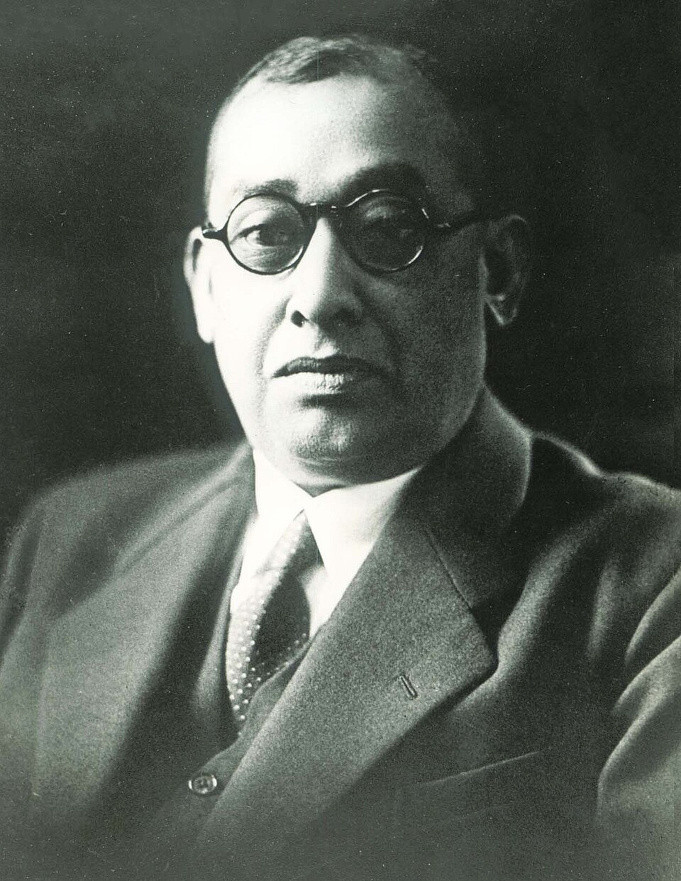 Black-and-white studio portrait of Indian revolutionary Rash Behari Bose, wearing round spectacles and a suit