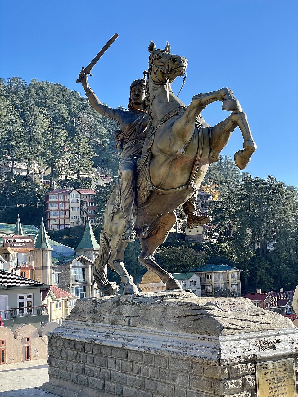 Equestrian statue of Rani Lakshmibai of Jhansi on a rearing horse, raising a sword with a child strapped to her back, on a stone pedestal