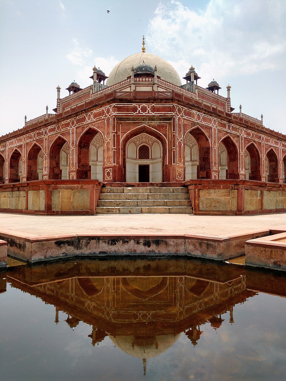 Humayuns Tomb in Delhi, a red sandstone Mughal mausoleum with a white marble dome and arched facades, reflected in a water channel