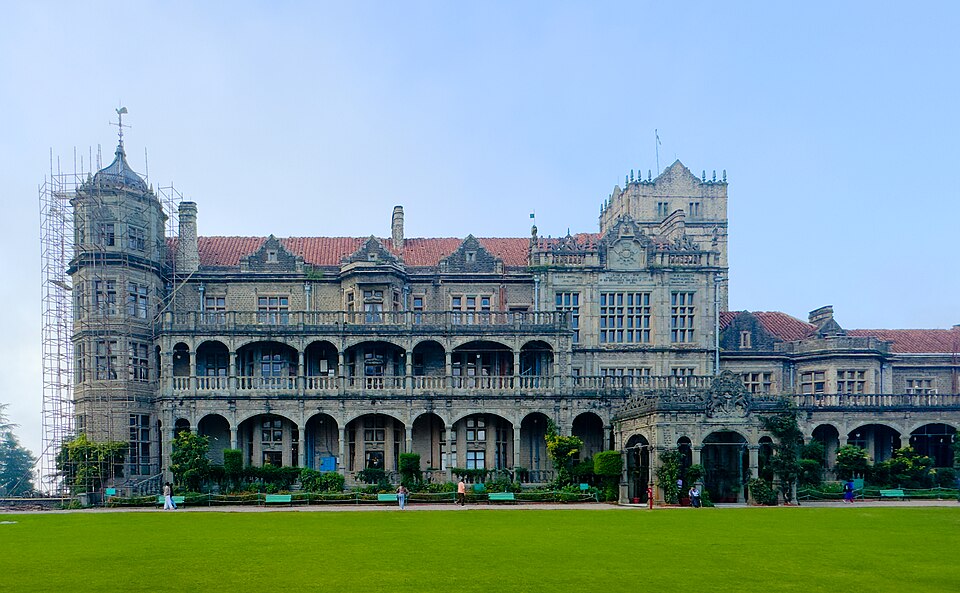 The grey stone Viceregal Lodge at Shimla, a many-gabled building with arcaded verandahs and a corner tower, seen across its front lawn