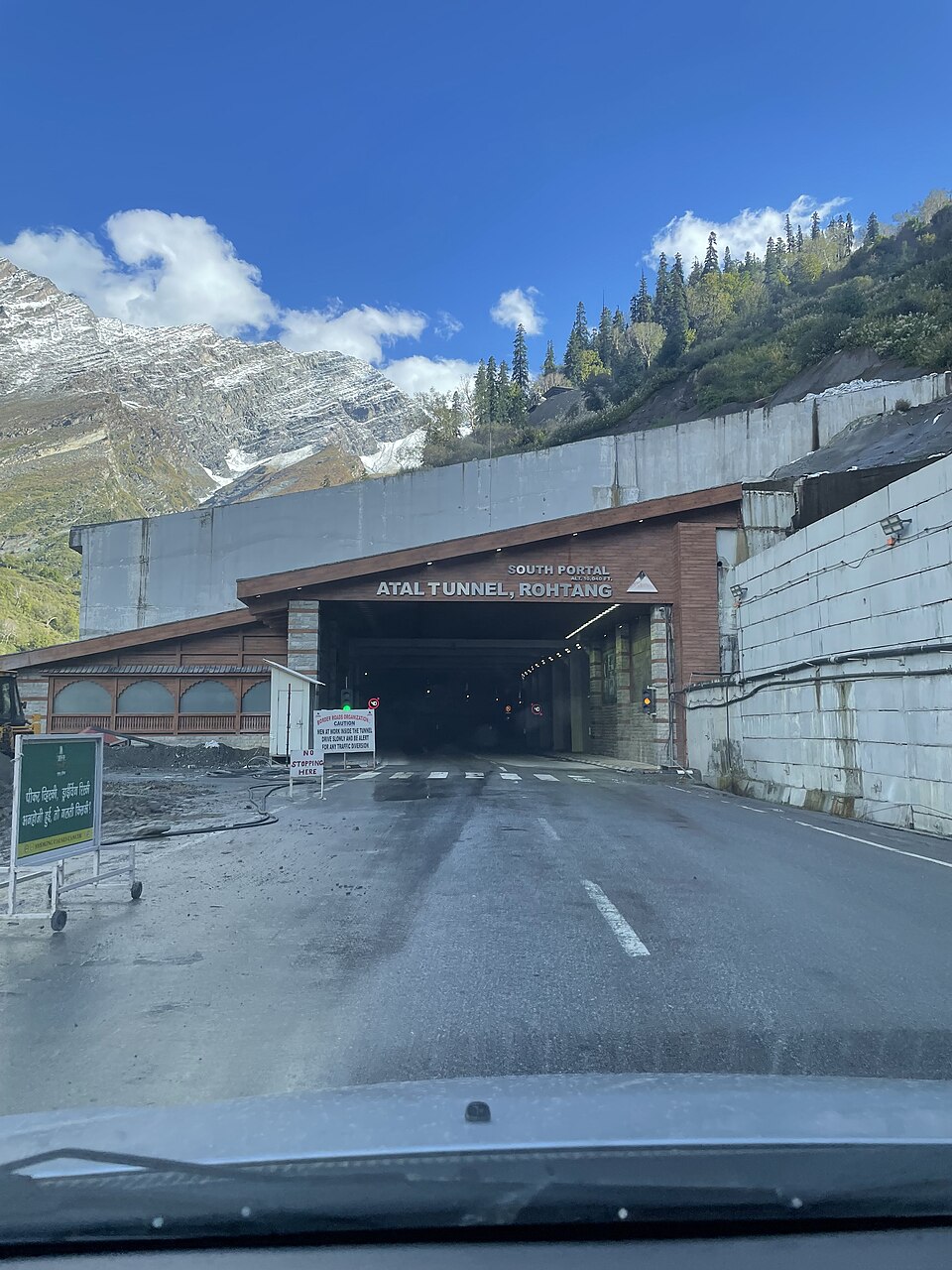 The south portal of the Atal Tunnel, its arch signed 'SOUTH PORTAL, ATAL TUNNEL, ROHTANG', with the road running into the lit tunnel and snow-streaked mountains rising behind